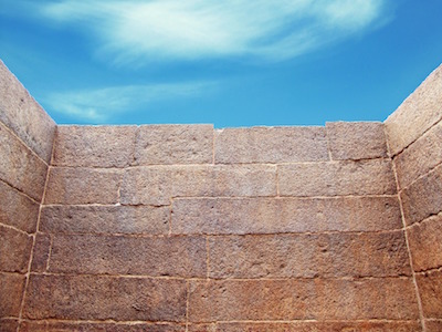A brick wall blocking the way forward, with blue skies above