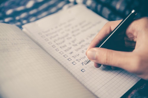 A pen held in a hand writes a checklist